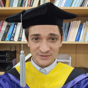 A photograph of Max wearing his cap and gown at Seoul National University.